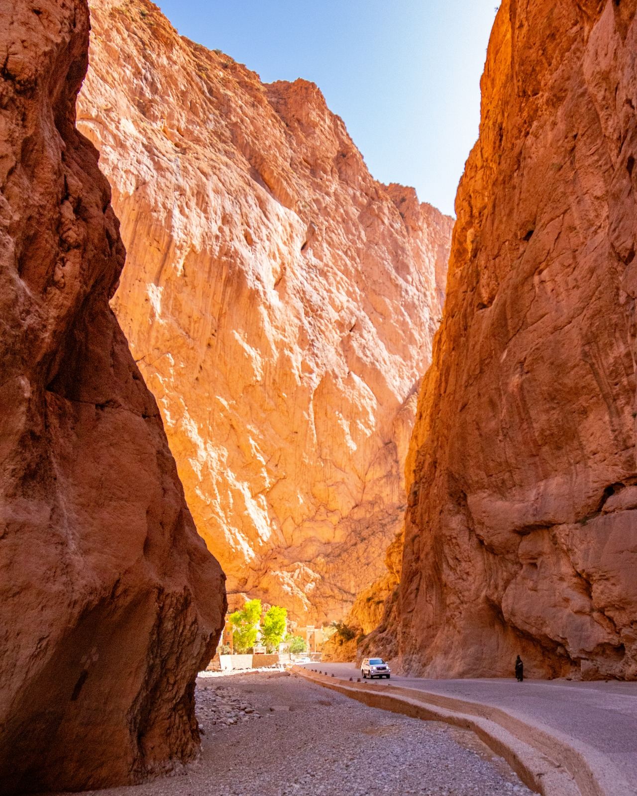 A narrow road winding between towering red canyon walls